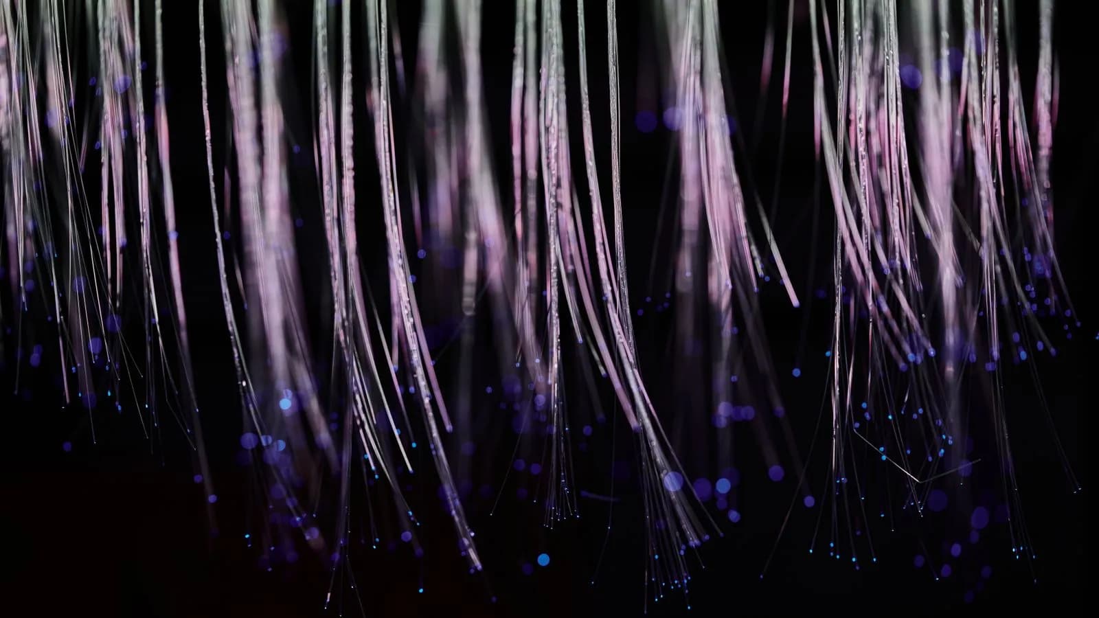 Glowing fiber-optic strands cascading on a dark background, representing an AI GTM engine surfacing dark-funnel signals