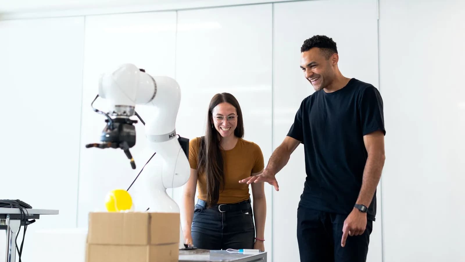Two engineers testing a robotic arm in a modern lab while developing custom AI systems